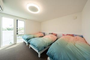 two beds in a room with a window at Villa NiuHale in Fujisawa