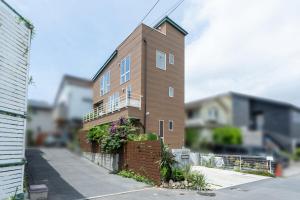 a brown brick building with a balcony on a street at Villa NiuHale in Fujisawa
