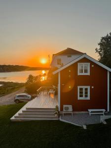 a house with a deck with the sunset in the background at New Timber Holiday Home With Bay Views in Kungshamn