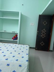 een slaapkamer met een bed en een kast met een deur bij JMS Villas in Tindivanam +1 foto