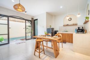 a kitchen and dining room with a wooden table and chairs at Villa The ARK - A by OriVista in Dalung