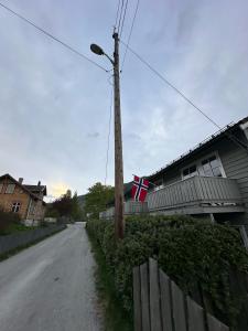 una bandera en un poste telefónico al lado de una casa en Rom i bofelleskap, en Sogndal