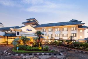 a hotel with a building with a courtyard at Prime Plaza Hotel Purwakarta in Cikampek