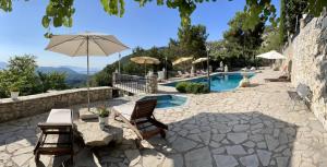 a patio with a table with an umbrella and a pool at Merlot Village Rental Apartments in Kariá