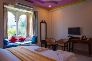 a bedroom with a bed and a window and a desk at Raj Kunj Haveli Kumbhalgarh in Rājsamand