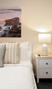 a bedroom with a bed and a nightstand with a lamp at Summery 3BR Home by Mel Airport, CBD & Watergardens in Sydenham