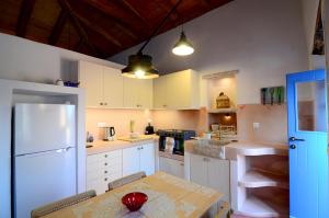 a kitchen with a table and a white refrigerator at Rodamia Traditional Cottage in Kythira