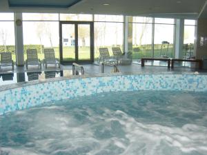 a large swimming pool with chairs and a table at Club 218 Wellness Stúdió in Siófok