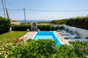 a villa with a swimming pool and lounge chairs at Artemida House in Artemida
