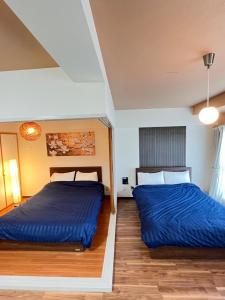 two beds in a room with blue sheets at 札幌駅近 すすきの中心部 スーペリアルーム最大7名 家族やグループにお勧め 市電駅前 北海道観光食事最高立地 11歳まで子供無料 高級ベッドマットレス使用 チェックアウト11時 in Sapporo