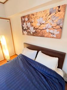 a bedroom with a bed and a painting on the wall at 札幌駅近 すすきの中心部 スーペリアルーム最大7名 家族やグループにお勧め 市電駅前 北海道観光食事最高立地 11歳まで子供無料 高級ベッドマットレス使用 チェックアウト11時 in Sapporo