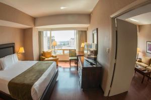 a hotel room with a large bed and a television at Clarion Suites Guatemala City in Guatemala