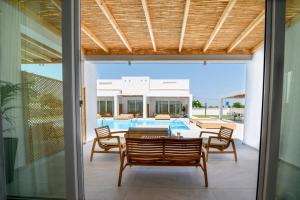 eine Terrasse mit Tisch und Stühlen und einem Pool in der Unterkunft Blue Summer Luxury Suites in Kourouta