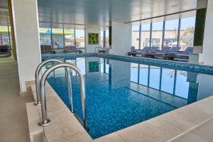 a large swimming pool in a building with blue water at Ozone Apartment Spa & Pool Beach Resort in Mamaia