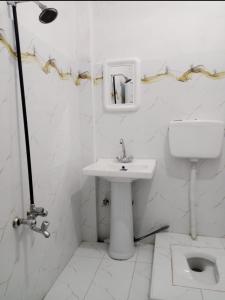 a white bathroom with a sink and a toilet at Ali Hotel in Kārandūkai
