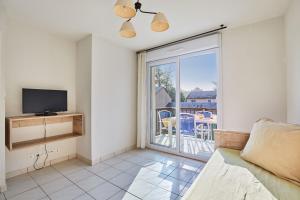 ein Wohnzimmer mit Couch und Fernseher und ein Balkon in der Unterkunft Résidence Odalys Le Hameau du Lac in Rignac
