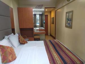 a hotel room with a bed and a bathroom at Empire Hotel in Mumbai +4 photos