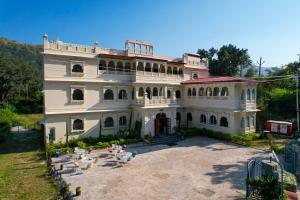 a large white house with chairs in front of it at Raj Kunj Haveli Kumbhalgarh in Rājsamand