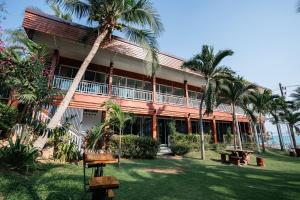 a building with palm trees in front of it at Baansuan Aokhai Beach Resort in Mae Pim