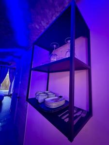 a black shelf with plates and glasses in a purple room at Capsule Nuage Jacuzzi Sauna in Fontaine-lʼÉvêque +19 photos