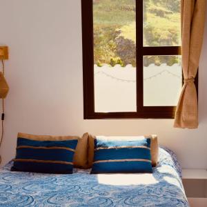 een bed met blauwe kussens in een kamer met een raam bij La Casa de las Estrella - Dúplex en Cazorla con bonitas vistas in Cazorla