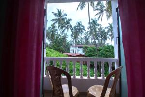 a balcony with two chairs and a view of palm trees at Hotel El - Paso in Arambol