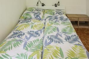 a bed in a bedroom with a bedspread with palm leaves at Albrecht2 in Celle