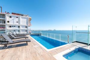 a balcony with chairs and a swimming pool on a building at Ocean View - 2 King Size with Homeoffice Space in Mazatlán