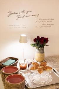 stół z talerzem jedzenia i wazonem róż w obiekcie Boutiquehotel Amadeus w mieście Salzburg +37 zdjęć