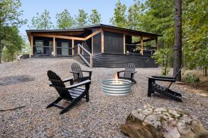a cabin in the woods with two chairs and a fire pit at Whispering Retreat Sleeps 4 in Broken Bow