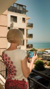 a woman standing on a balcony looking at the ocean at Flat Lora Pomorie in Pomorie