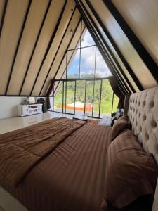 a large bed in a room with a large window at glamping anugrah in Tegalharendong