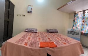 a bedroom with a bed with orange pillows on it at Jaykishan sadan in Varanasi