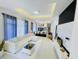 a living room with a white couch and a tv at Gimhani Villa Hiriketiya in Dickwella