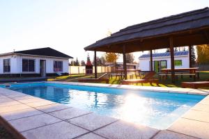 a swimming pool with a gazebo and picnic tables at Casa de montaña azul in Las Compuertas