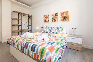 ein Schlafzimmer mit einem Bett mit einer bunten gestreiften Tagesdecke in der Unterkunft Santander Centro I 4 hab I Ocio I Wifi I Moderno in Santander