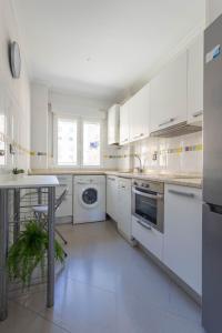 eine weiße Küche mit weißen Geräten und einem Tisch in der Unterkunft Santander Centro I 4 hab I Ocio I Wifi I Moderno in Santander