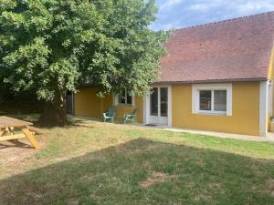 ein gelbes Haus mit einem Picknicktisch und einem Baum in der Unterkunft Gite l'Amical in Roézé-sur-Sarthe