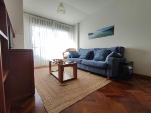 a living room with a blue couch and a table at Apartamento centro de Sada in Sada