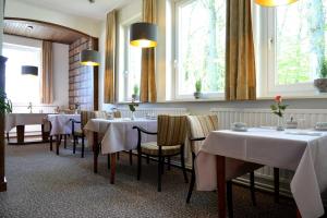 un restaurante con mesas y sillas blancas y ventanas en Arnimsruh Hotel garni, en Lübeck