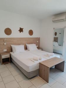 a bedroom with a large white bed and a table at Milies Apartments in Stavros