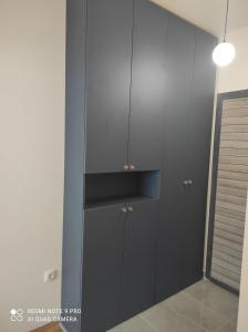 a kitchen with black cabinets and a blue wall at Lullaby apartment 2, moderan stan sa spavaćom sobom i privatnom garažom in Bijeljina