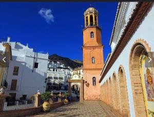 un bâtiment avec une tour d'horloge dans une ville dans l'établissement Sunshine Home Competa, à Cómpeta