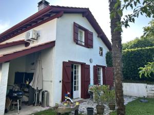 a white house with red doors and a tree at Maison familiale entre océan, golf & forêt in Anglet
