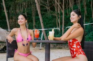 two women in bathing suits sitting at a table with drinks at Chindonan Dive and Beach Resort in Coron