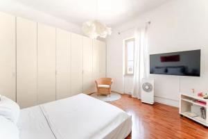 Un dormitorio blanco con una cama y un televisor. en Casa della Salita San Pietro, en Roma