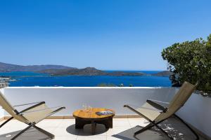 a table and chairs on a patio with a view of the ocean at Elounda Black Pearl Villa in Agios Nikolaos