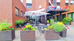 eine Terrasse mit Tisch, Stühlen und Sonnenschirm in der Unterkunft Hotel Panorama Hamburg-Billstedt in Hamburg