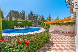 モナチルにあるVilla Leonor con piscina privadaのプールと花が咲くパティオのある裏庭