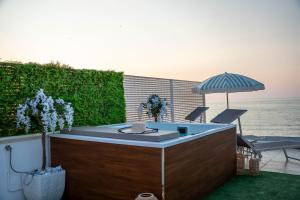 a hot tub with an umbrella next to the ocean at Amarè Luxury Suite And Room Vista Mare in Bari